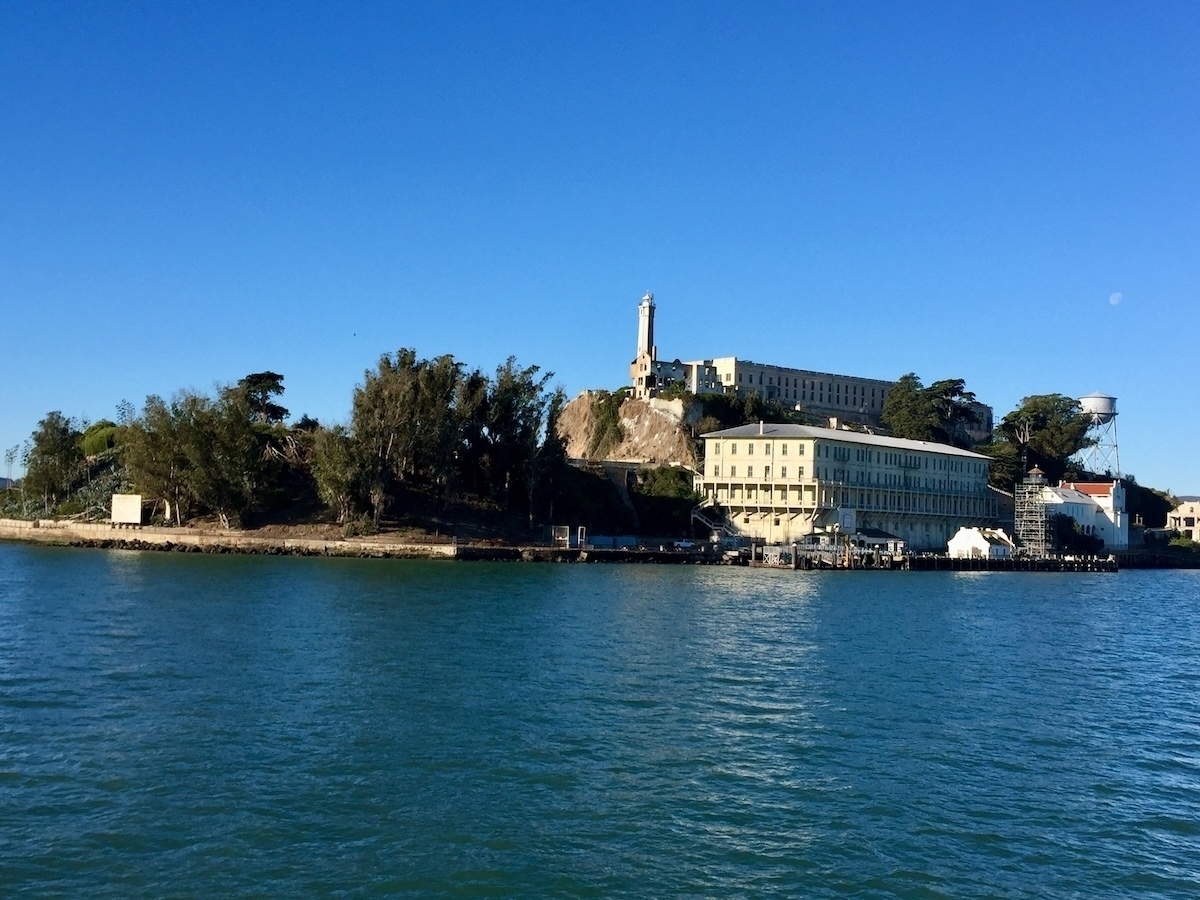 Auto-generated description: A view of Alcatraz Island, featuring the historic prison buildings surrounded by clear blue waters.