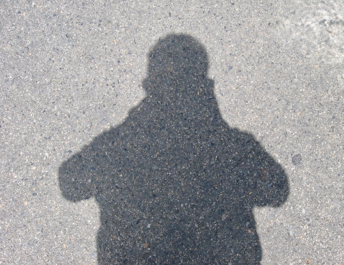 Auto-generated description: A person's shadow is cast on a textured, gray surface.
