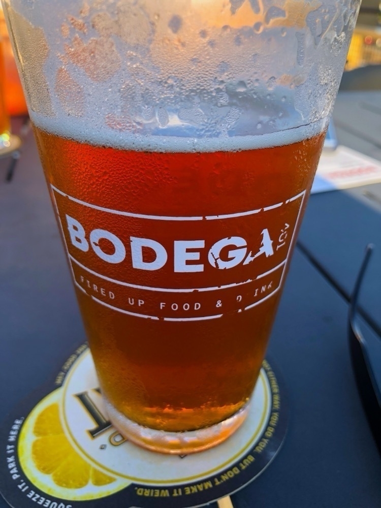 A glass of amber beer with the logo 'BODEGA 41°' printed on it rests on a table with a matching coaster.