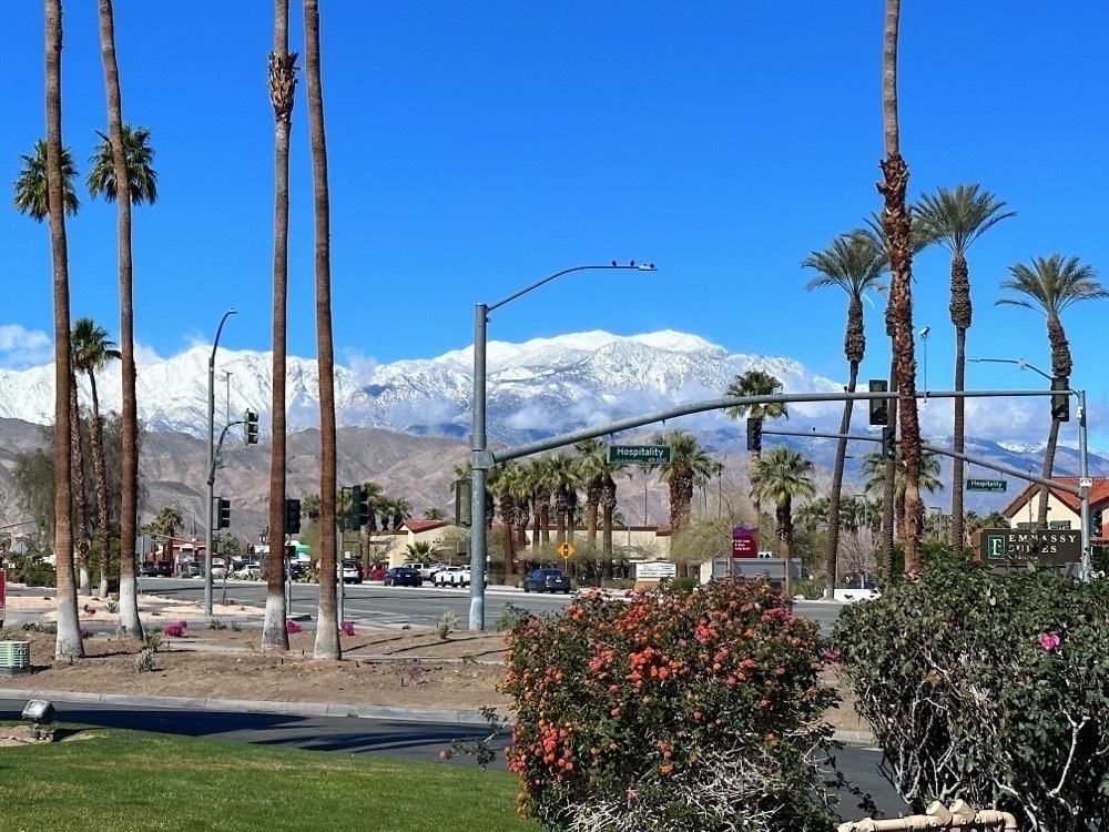 A snowy mountain range with buildings in the foreground.