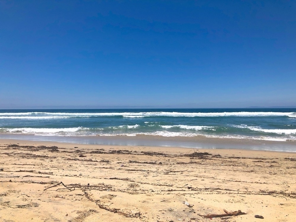 A sandy beach viewing the ocean with small waves.